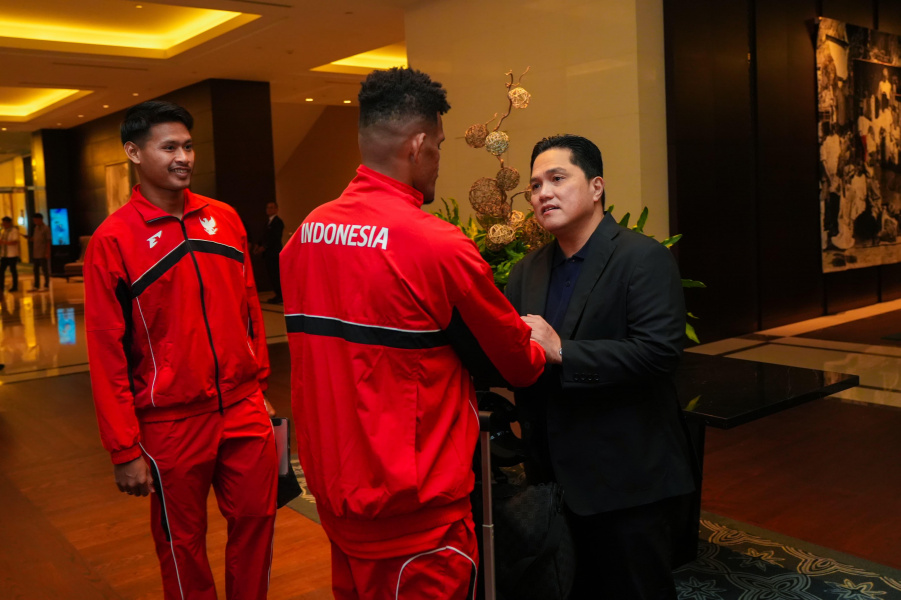 Erick Thohir tengah berjabat tangan dengan salah satu pemain Timnas Indonesia.